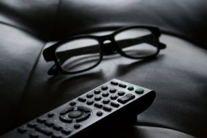grayscale photo of remote control near eyeglasses smart home