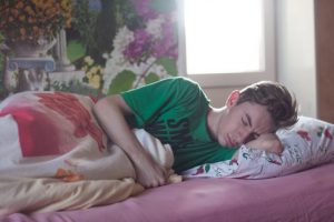 man wearing green printed crew neck shirt while sleeping in guest bedroom