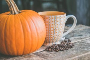 orange pumpkin near white ceramic mug with seeds